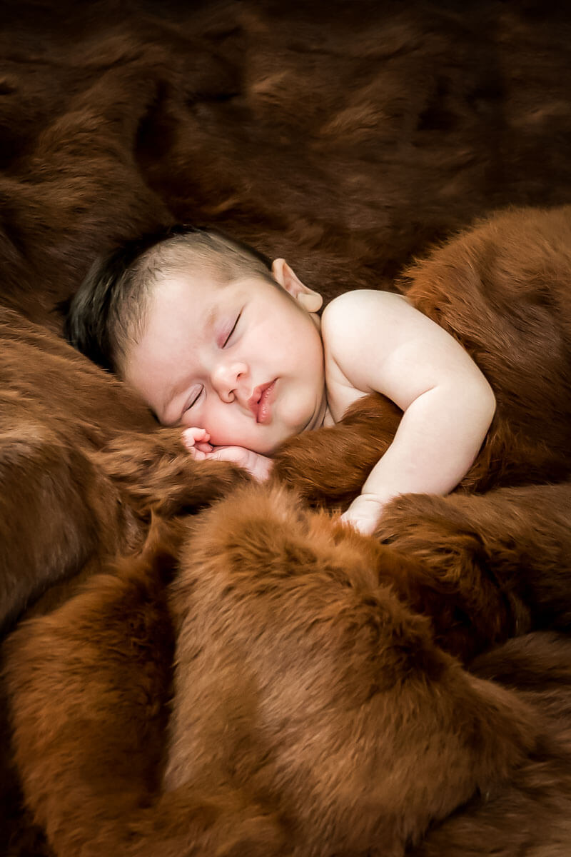 Sleeping newborn snuggled in heirloom coat